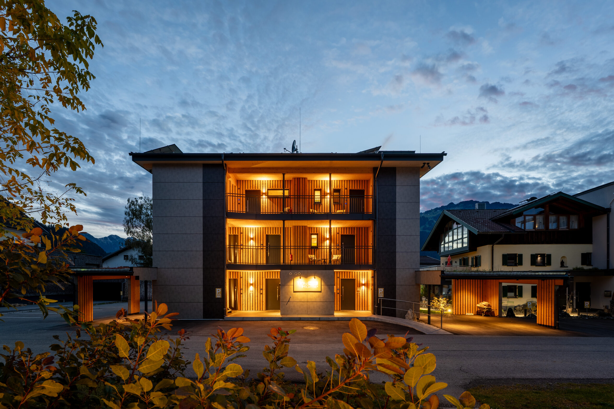 Holzbau Saurer Tinyhome Singer Aussenaufnahme Dämmerung Beleuchtung Aufgänge