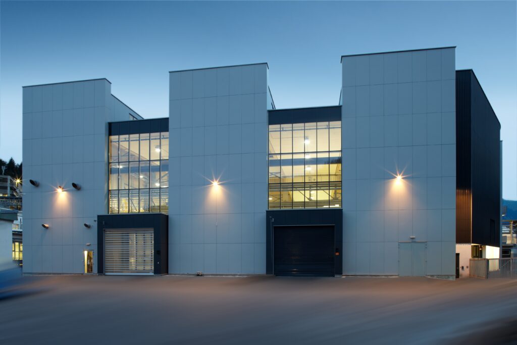 Produktionshalle Oberflächentechnik ästhetischer Holzarchitektur technische Funktionalität Nachtaufnahme Verglasung