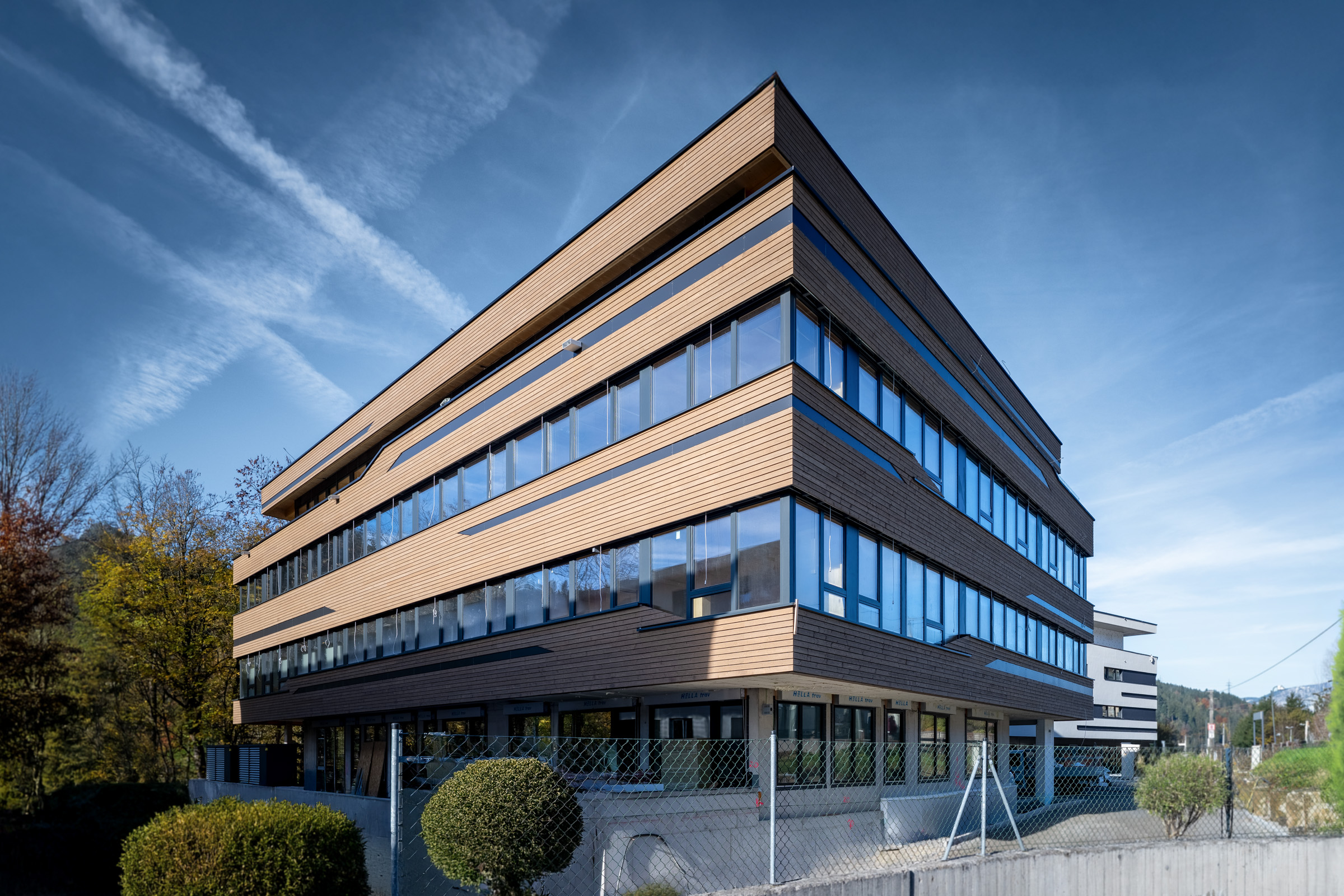Referenz Holzbau Saurer Gewerbebau Bürogebäude Pletzer Tagesaufnahme Seitenansich eingebetet in Landschaft Herbst moderne Fassade Verglasung